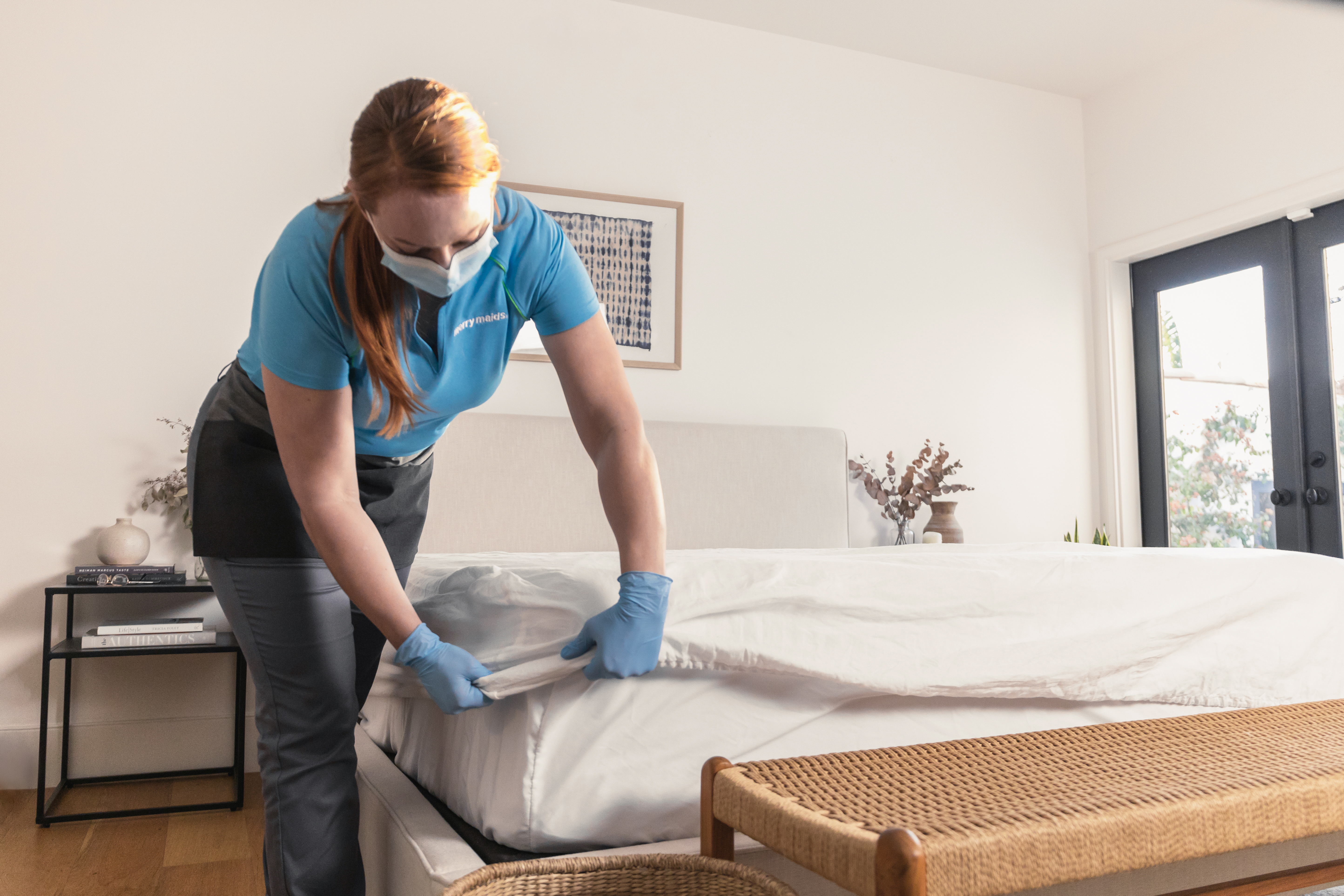 A Merry Maids house cleaner making a bed