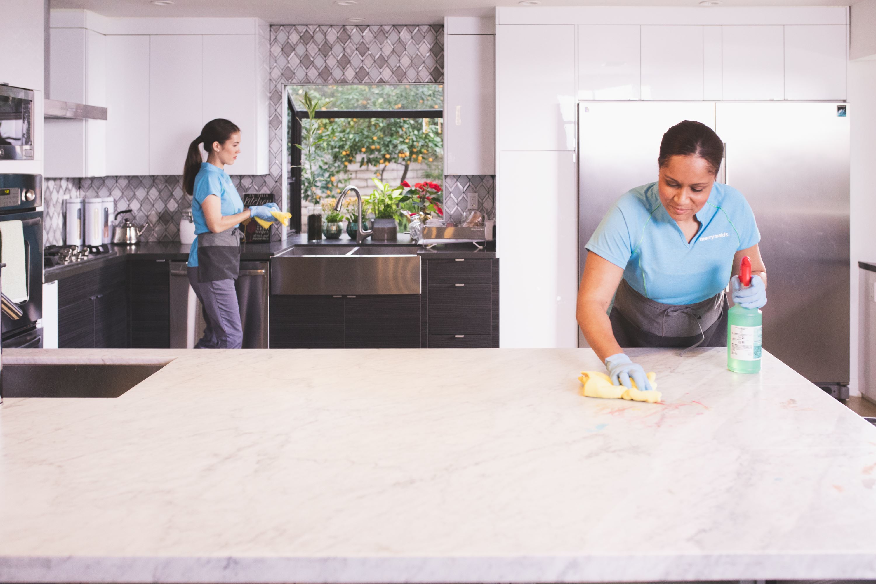 Merry Maids team members sanitizing a kitchen during maid services
