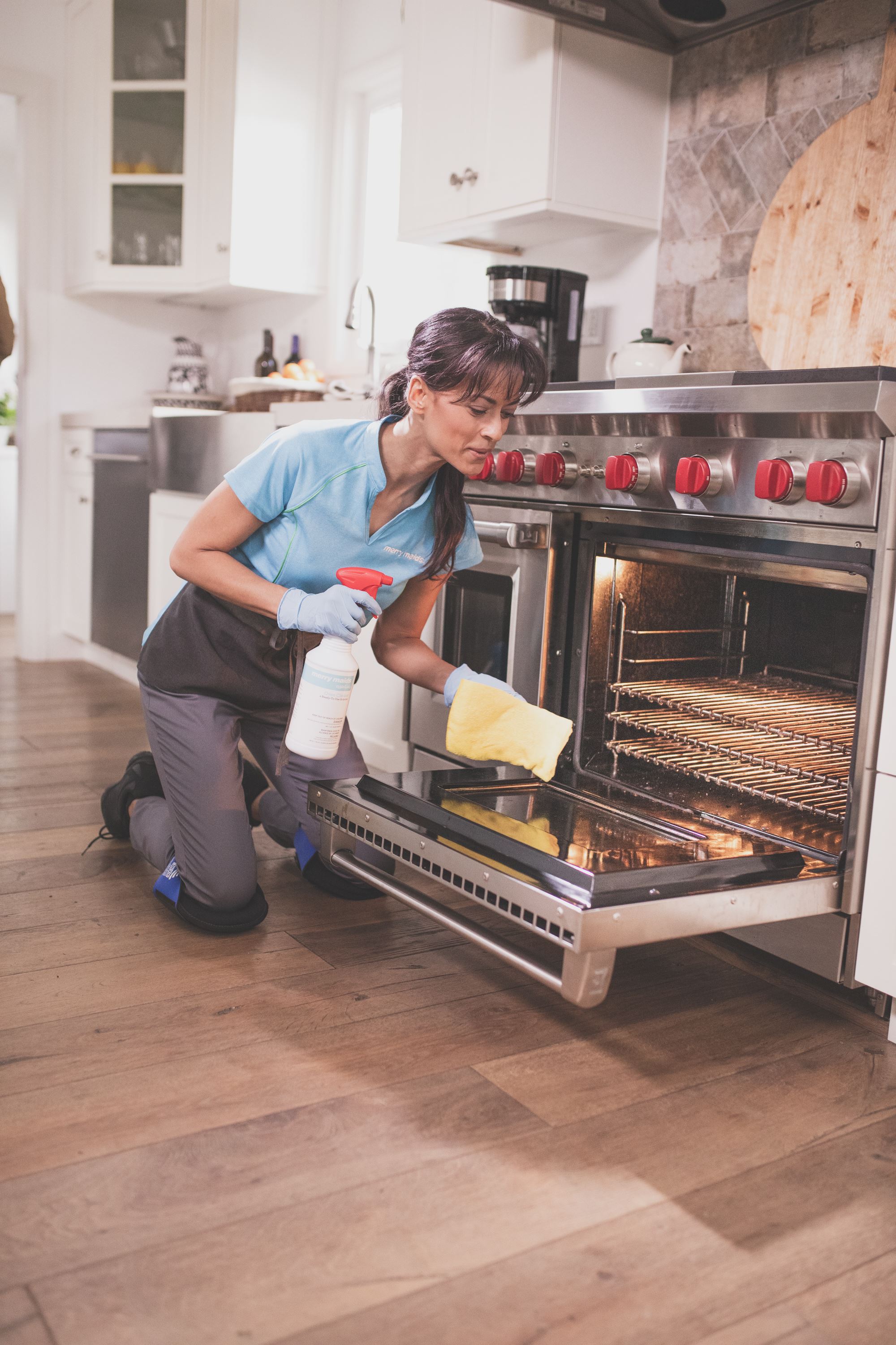 A Merry Maids team member wiping down an oven door during maid service in Gainesville, Georgia