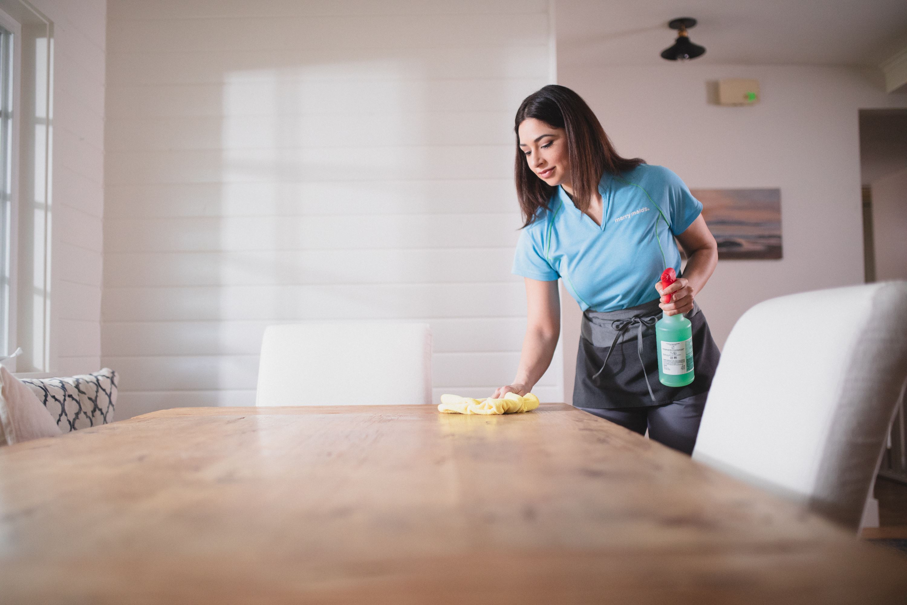 A Merry Maids team member wiping down a table during move in cleaning