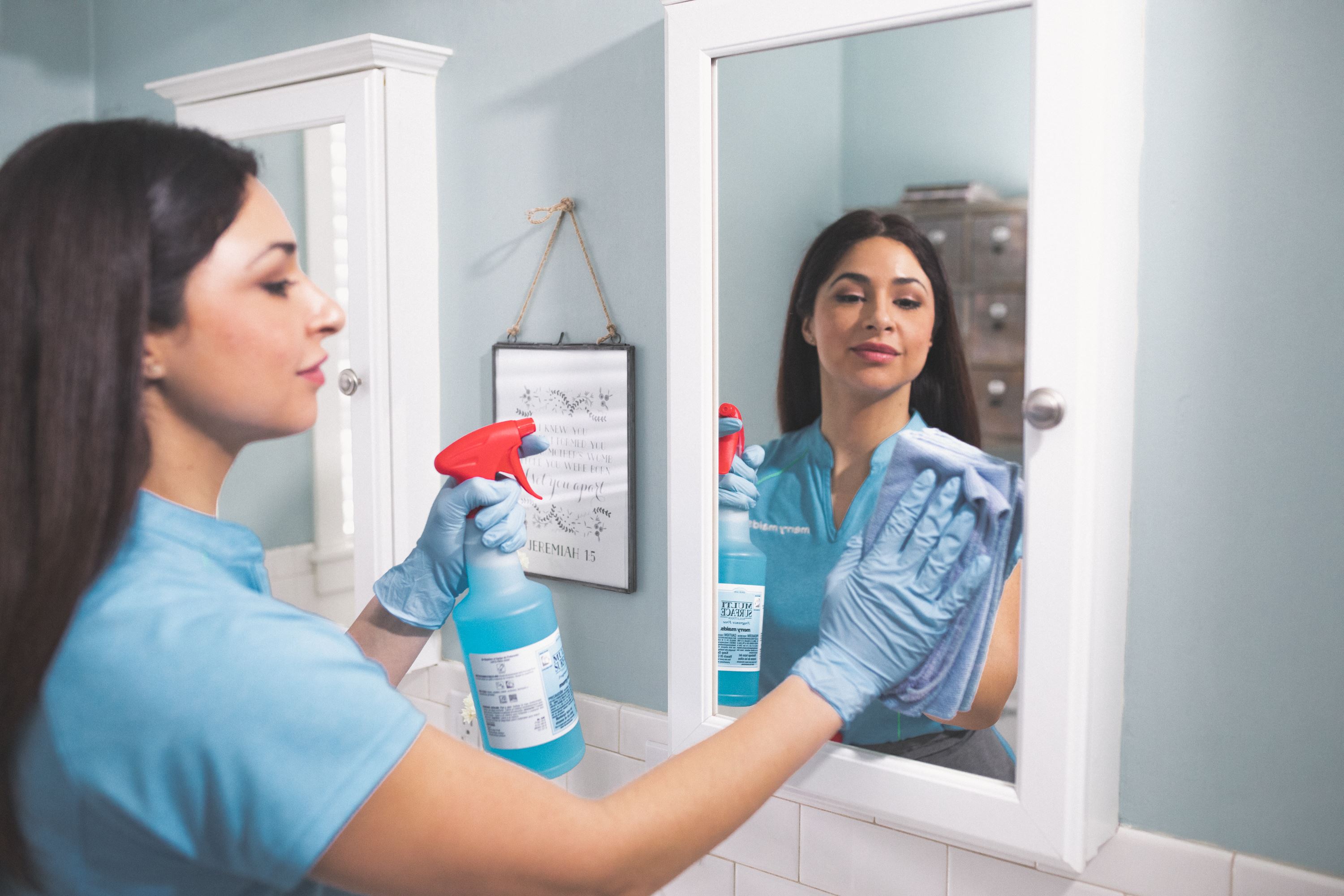 Merry Maids team member disinfecting a bathroom mirror during maid service in Knoxville 
