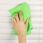 Cleaning blinds with green cloth