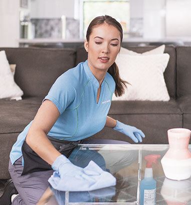 A Merry Maids house cleaner in Riverview disinfects a coffee table