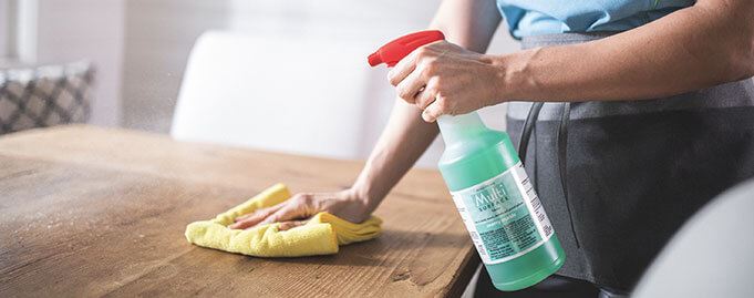 Merry Maids maid sanitizing and wiping down a table