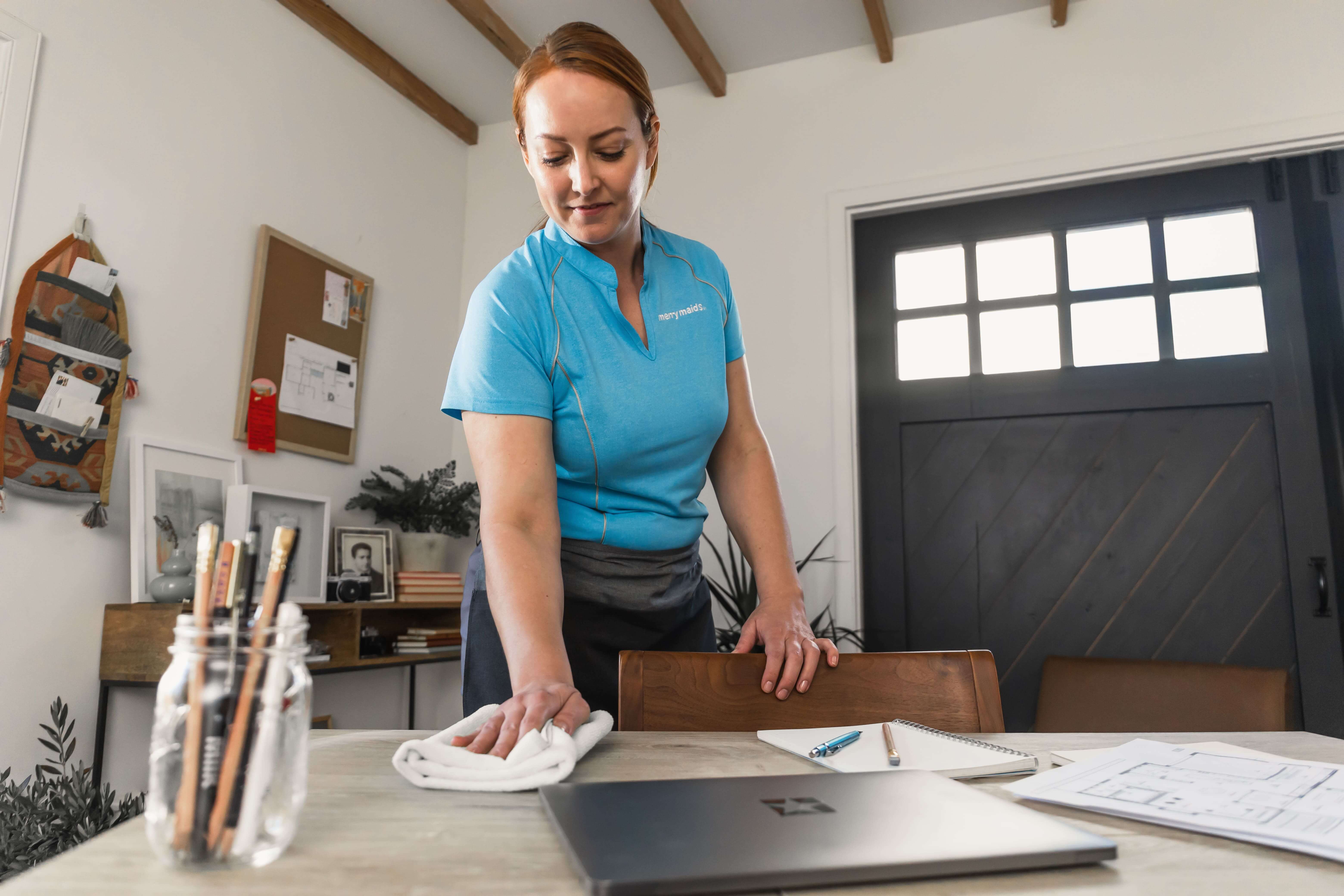 Merry Maids professional wiping desk during house cleaning service