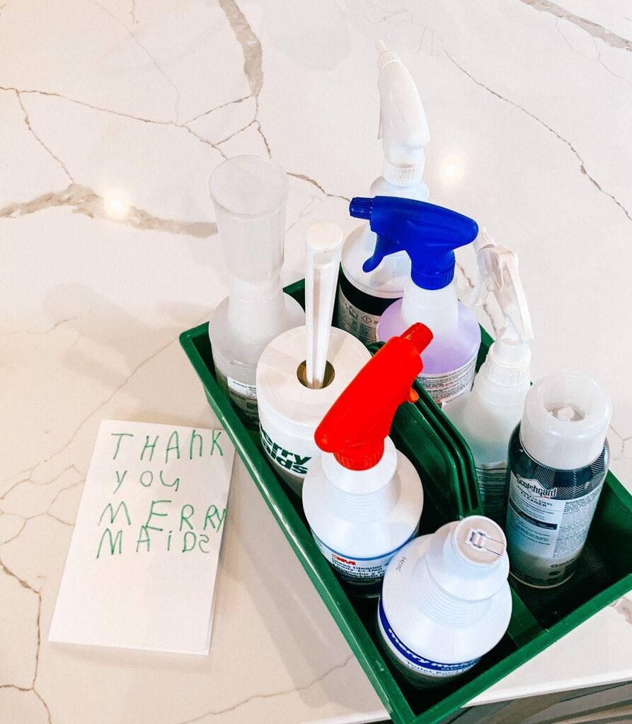  Cleaning products in a caddy prepared for green cleaning services, next to a note in a child’s handwriting that reads “Thank You Merry Maids”