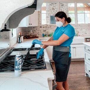 House cleaner wiping stovetop in kitchen